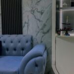 Stylish living room with a blue tufted sofa and modern marble wall backdrop.